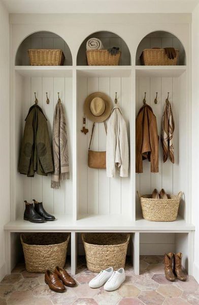 Built-in mudroom organization featuring three individual cubbies with upper arched storage, integrated bench seating, and lower storage compartments, all grounded by hexagon tile flooring