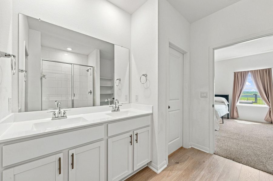 A contemporary double vanity restroom opens directly into a sunlit bedroom space.