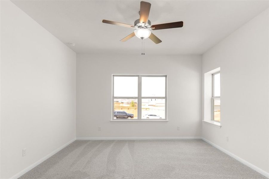 Spare room featuring plenty of natural light, light colored carpet, baseboards, and a ceiling fan
