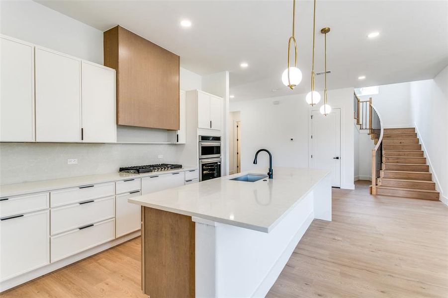 Kitchen featuring an island with sink, appliances with stainless steel finishes, light wood-style floors, recessed lighting, and white cabinets Kitchen featuring an island with sink, appliances with stainless steel finishes, light wood-style floors, recessed lighting, and white cabinets
