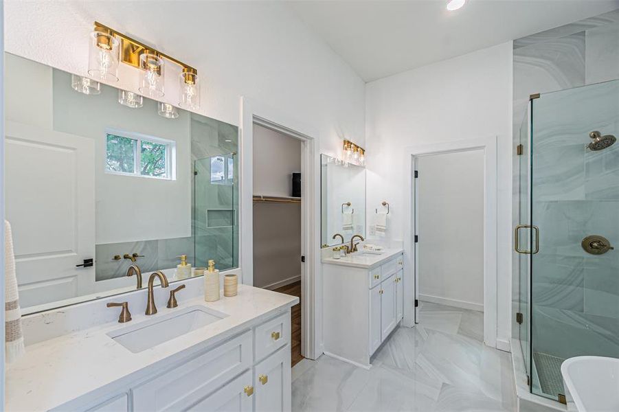 Full bath featuring a marble finish shower, two vanities, a walk in closet, and a freestanding bath