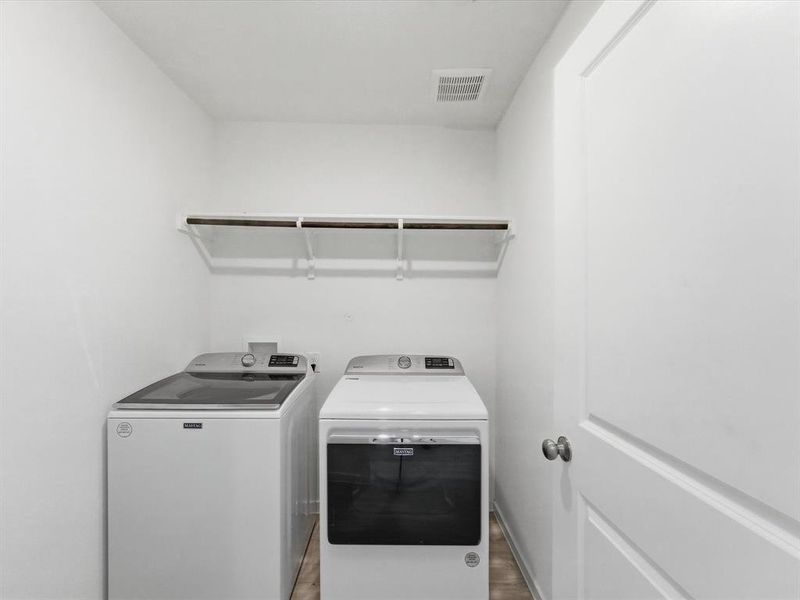 Dedicated laundry area featuring a top-load washing machine, front-load dryer, and wall-mounted shelving