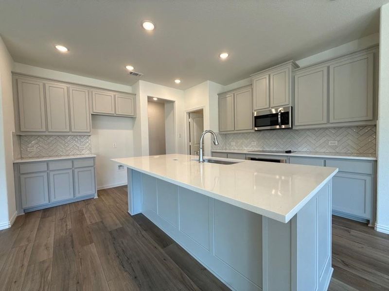 Kitchen featuring light stone counters, tasteful backsplash, dark wood-style flooring, and recessed lighting