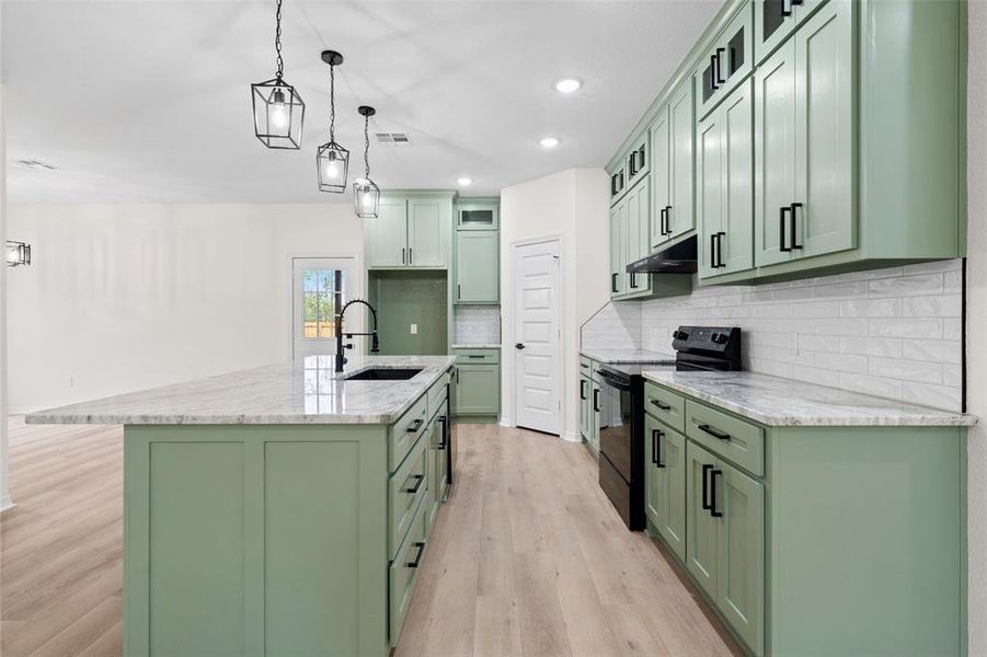 Kitchen featuring green cabinetry, light stone counters, black / electric stove, and recessed lighting
