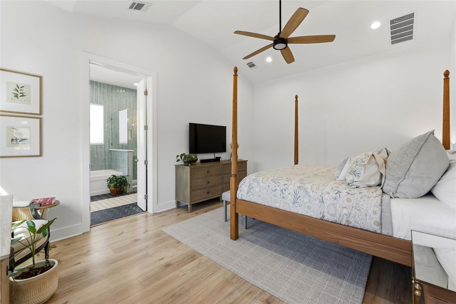 Bedroom with light wood-style floors, ceiling fan, vaulted ceiling, recessed lighting, and ensuite bathroom