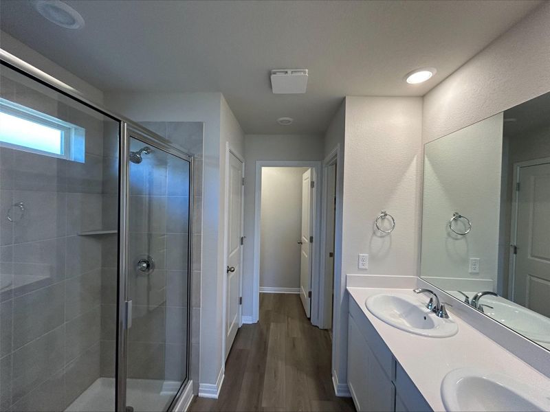 Bathroom featuring a stall shower, dark wood-type flooring, double vanity, and a closet Bathroom featuring a stall shower, dark wood-type flooring, double vanity, and a closet