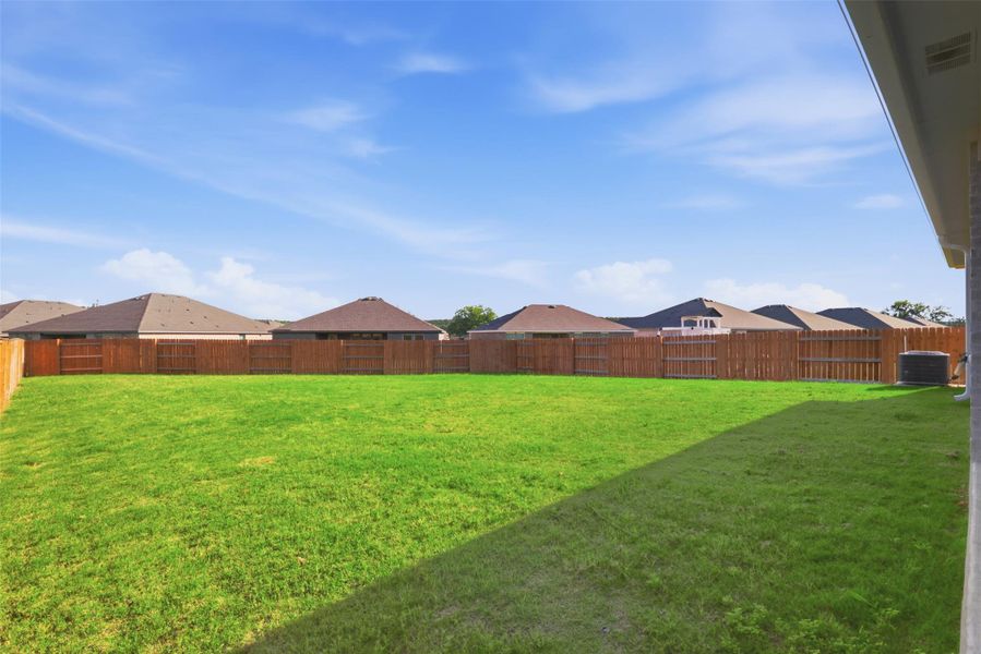 Expansive fenced backyard featuring a manicured lawn and a privacy fence
