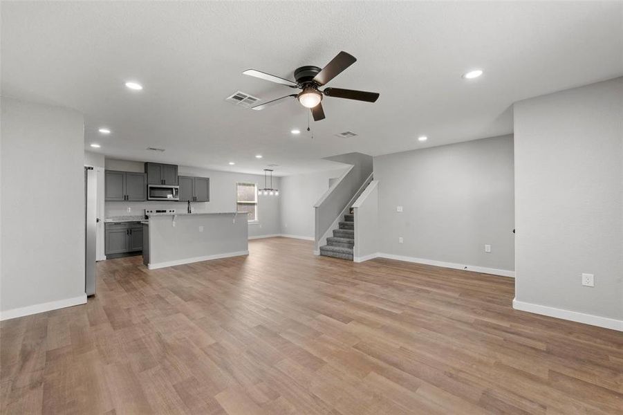 Unfurnished living room with ceiling fan, recessed lighting, stairs, and light wood-style flooring Unfurnished living room with ceiling fan, recessed lighting, stairs, and light wood-style flooring