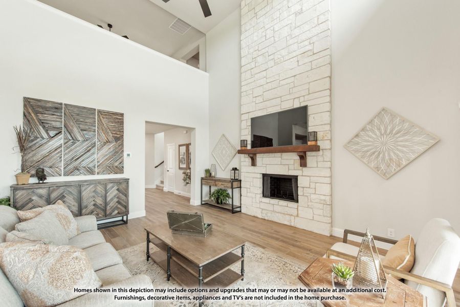 Living room with two-story stone fireplace, wood mantel, hardwood floors, and neutral furnishings
