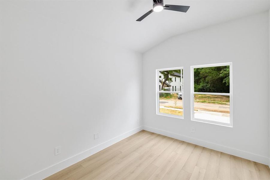 Spare room featuring lofted ceiling, light wood finished floors, and a ceiling fan