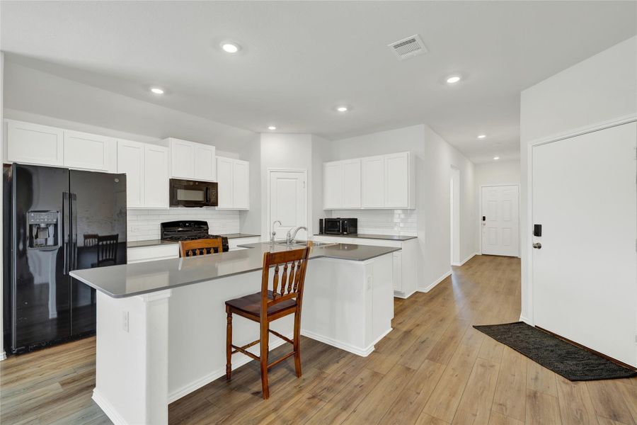 A contemporary kitchen space boasts abundant white cabinetry, sleek countertops, and a functional center island.
