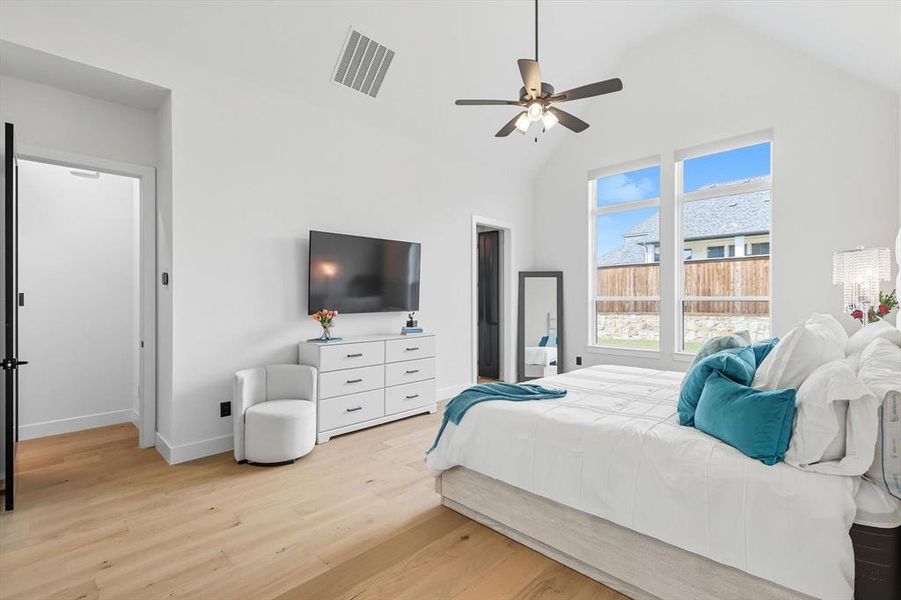 Primary Bedroom with light hardwood floors, ceiling fan, and high vaulted ceiling Primary Bedroom with light hardwood floors, ceiling fan, and high vaulted ceiling