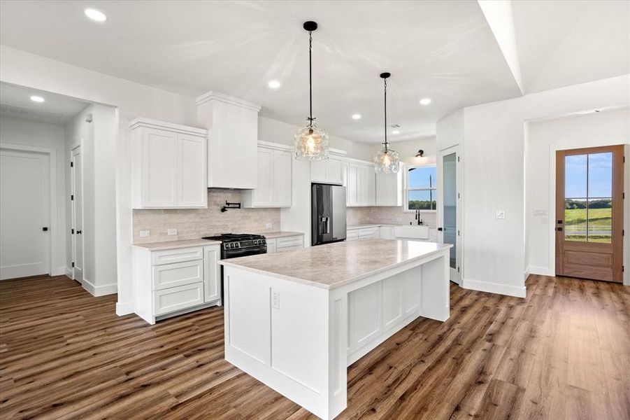 Kitchen with white cabinets, tasteful backsplash, stainless steel fridge, and recessed lighting Kitchen with white cabinets, tasteful backsplash, stainless steel fridge, and recessed lighting