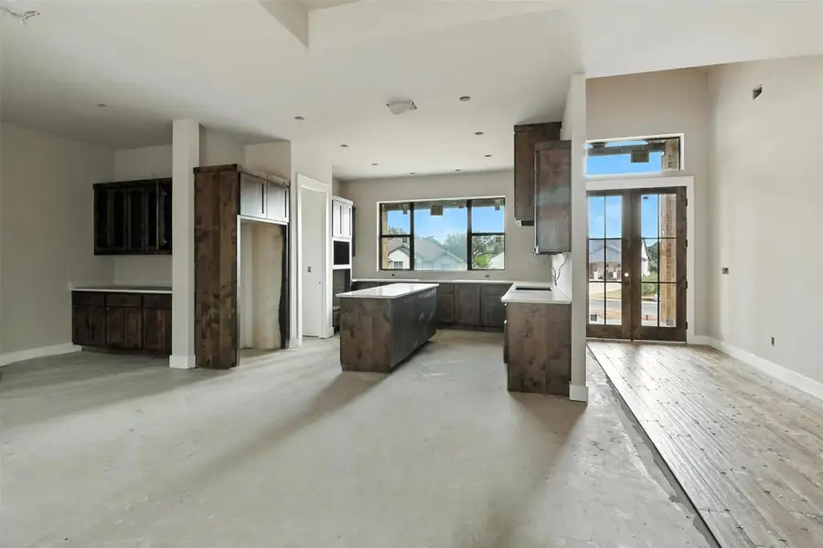 Kitchen featuring dark brown cabinets, a center island, french doors, and concrete floors Kitchen featuring dark brown cabinets, a center island, french doors, and concrete floors