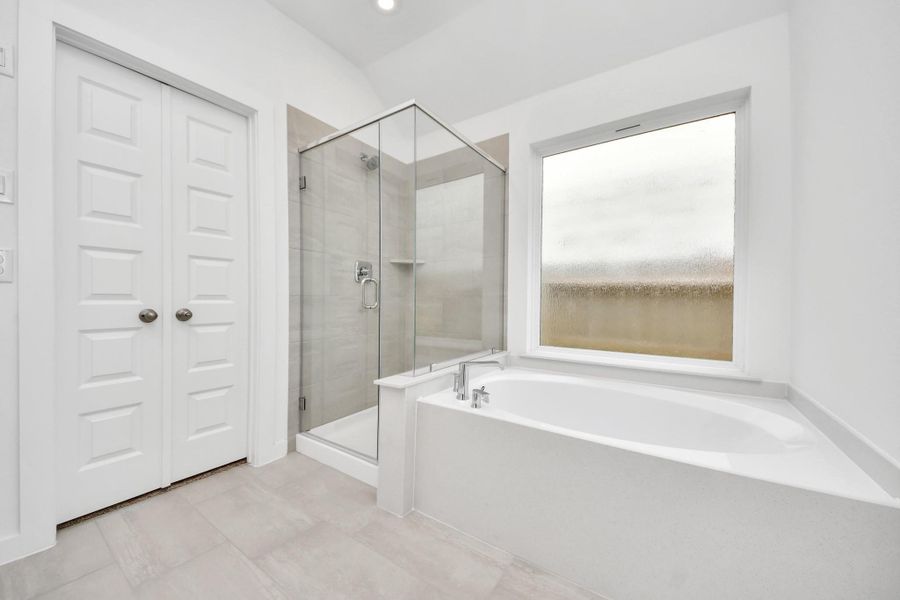 Indulge in a spa-like retreat within the confines of this primary bathroom. Delight in a spacious walk-in shower enveloped in stylish tile surround, unwind in a separate garden tub adorned with custom detailing. Sample photo of completed home with similar floor plan. Actual colors and selections may vary. Indulge in a spa-like retreat within the confines of this primary bathroom. Delight in a spacious walk-in shower enveloped in stylish tile surround, unwind in a separate garden tub adorned with custom detailing. Sample photo of completed home with similar floor plan. Actual colors and selections may vary.