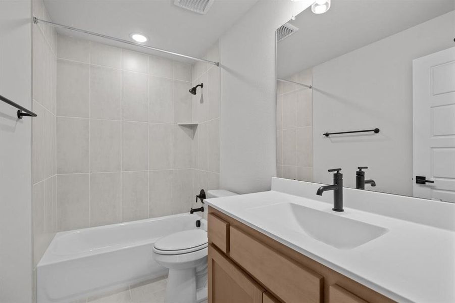 Bathroom featuring a vanity with light wood-finish cabinetry and a white countertop, a rectangular undermount sink, and a matte black faucet Bathroom featuring a vanity with light wood-finish cabinetry and a white countertop, a rectangular undermount sink, and a matte black faucet