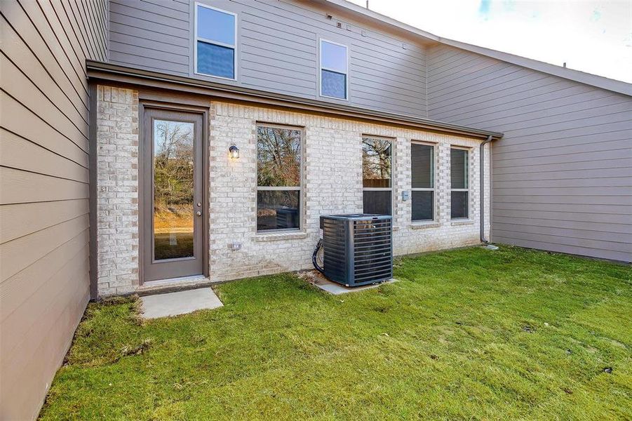 Back of house featuring cooling unit and a lawn