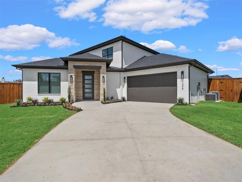 View of front of property featuring a garage, central air condition unit, and a front lawn