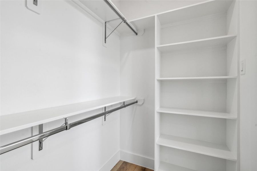 This walk in closet also comes equipped with custom shelves and sleek metal rods to tie the room together. This walk in closet also comes equipped with custom shelves and sleek metal rods to tie the room together.