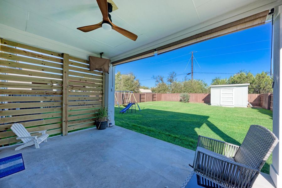Fenced backyard featuring a patio, a storage shed, ceiling fan, and a playground