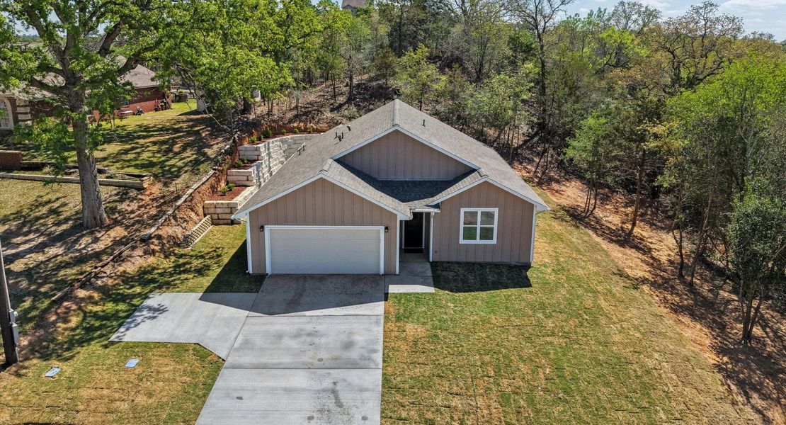 View of front of house featuring a garage, driveway, a front lawn, and board and batten siding