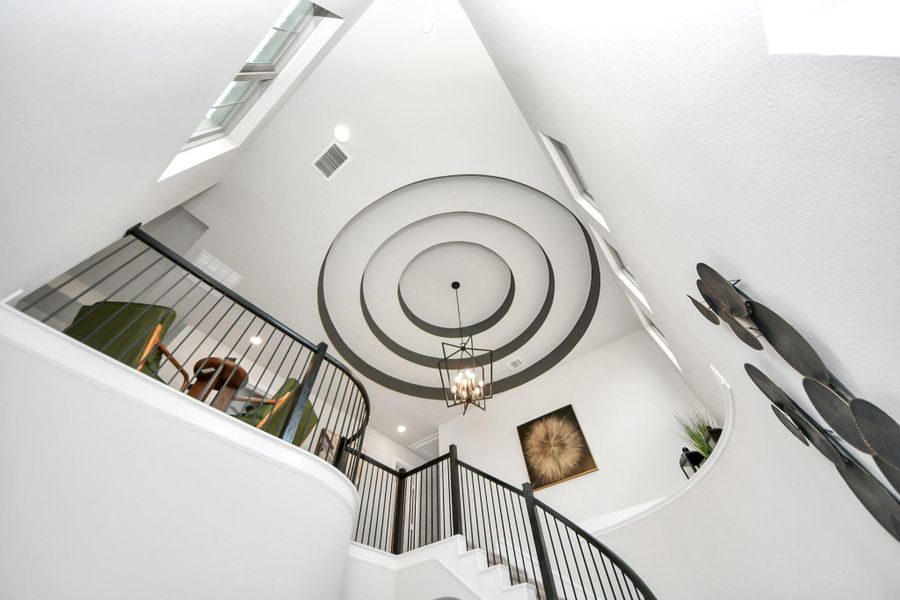 Statement foyer with designer circular tray ceiling, modern lighting, and open landing.