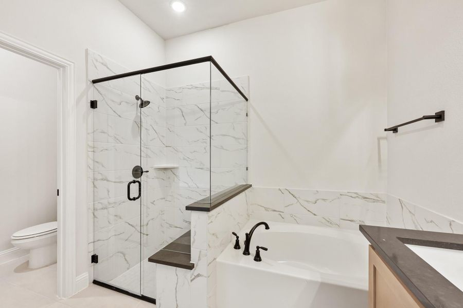 Bathroom with glass-enclosed shower, soaking tub, and marble tile walls with black fixtures