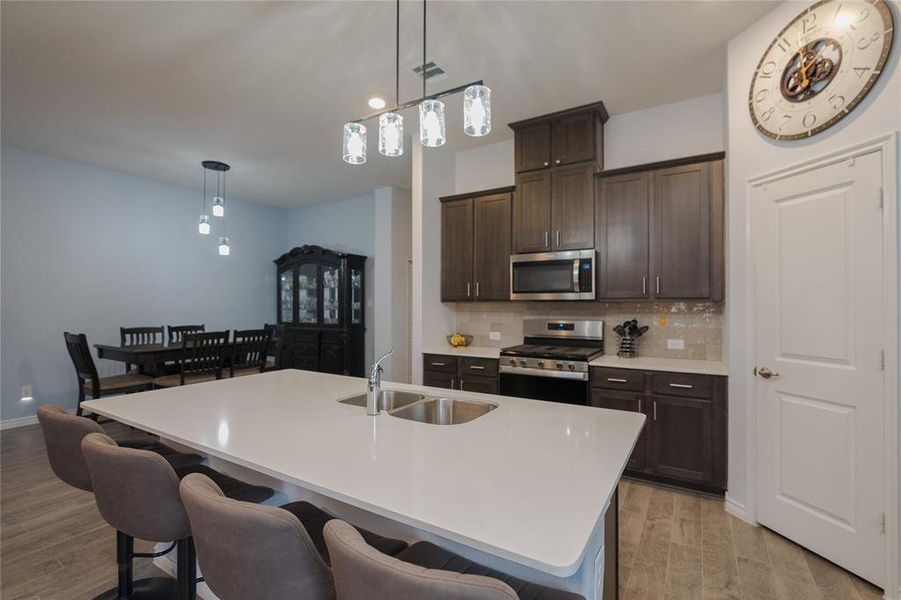 Kitchen featuring light hardwood / wood-style floors, sink, appliances with stainless steel finishes, and an island with sink