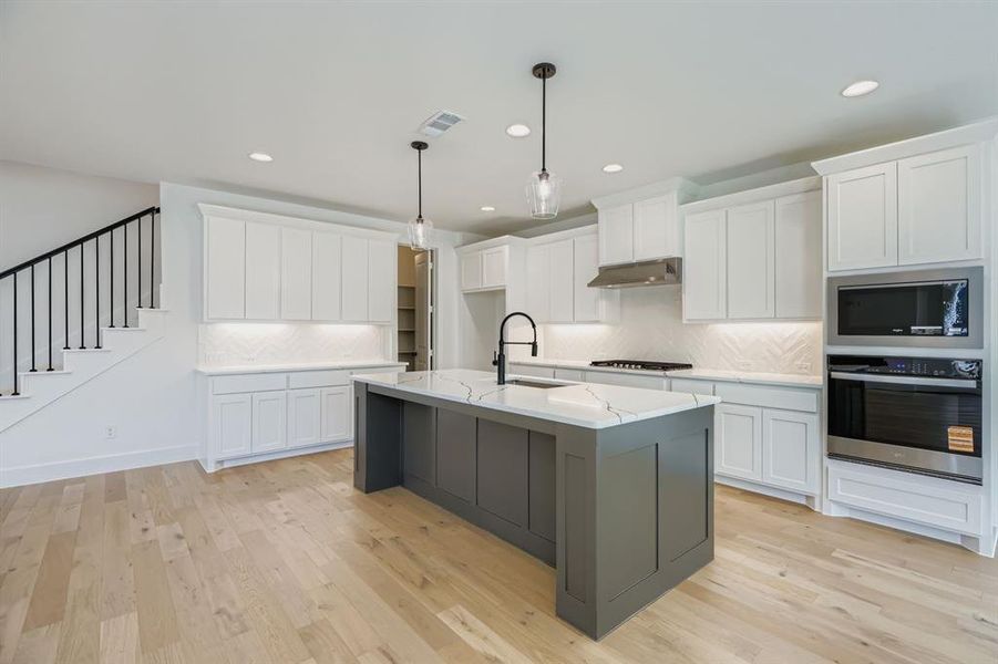 Kitchen with decorative backsplash, stainless steel appliances, white cabinets, pendant lighting, and recessed lighting