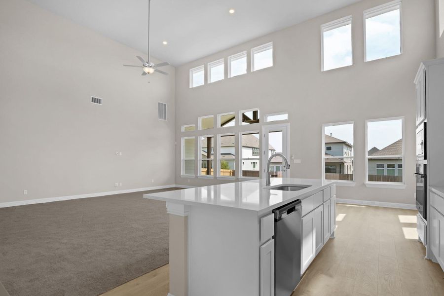 Kitchen featuring stainless steel dishwasher, a sink, light countertops, a high ceiling, and visible vents Kitchen featuring stainless steel dishwasher, a sink, light countertops, a high ceiling, and visible vents