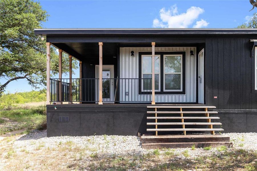 Modern black exterior with a covered porch featuring natural wood posts