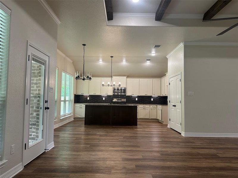 Kitchen featuring ornamental molding, a chandelier, dark wood-type flooring, backsplash, and white cabinets Kitchen featuring ornamental molding, a chandelier, dark wood-type flooring, backsplash, and white cabinets