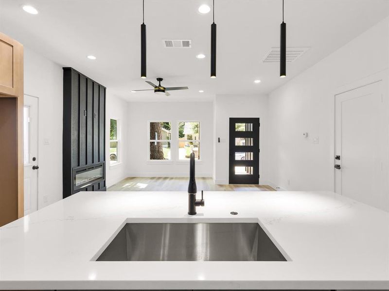 Kitchen featuring light brown cabinets, ceiling fan, light hardwood / wood-style floors, hanging light fixtures, and sink