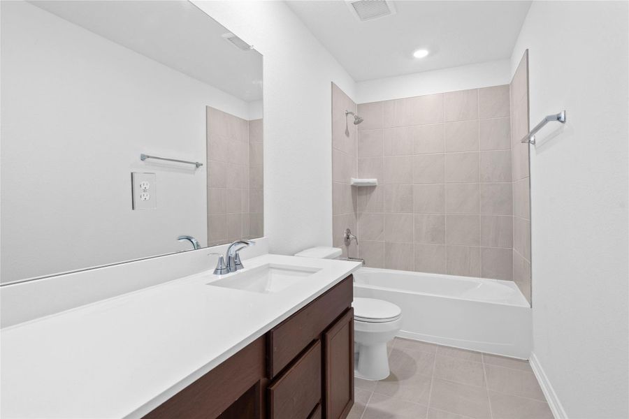 The secondary bathroom showcases tile flooring, a bath/shower combo with Daltile tile surround, vanity with knee space and a stunning light countertop, a stylish mirror, sleek fixtures, and contemporary finishes throughout. The secondary bathroom showcases tile flooring, a bath/shower combo with Daltile tile surround, vanity with knee space and a stunning light countertop, a stylish mirror, sleek fixtures, and contemporary finishes throughout.