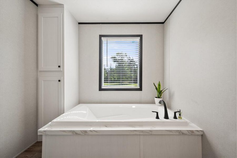 Soaking tub with black fixtures, and a window with blinds Soaking tub with black fixtures, and a window with blinds