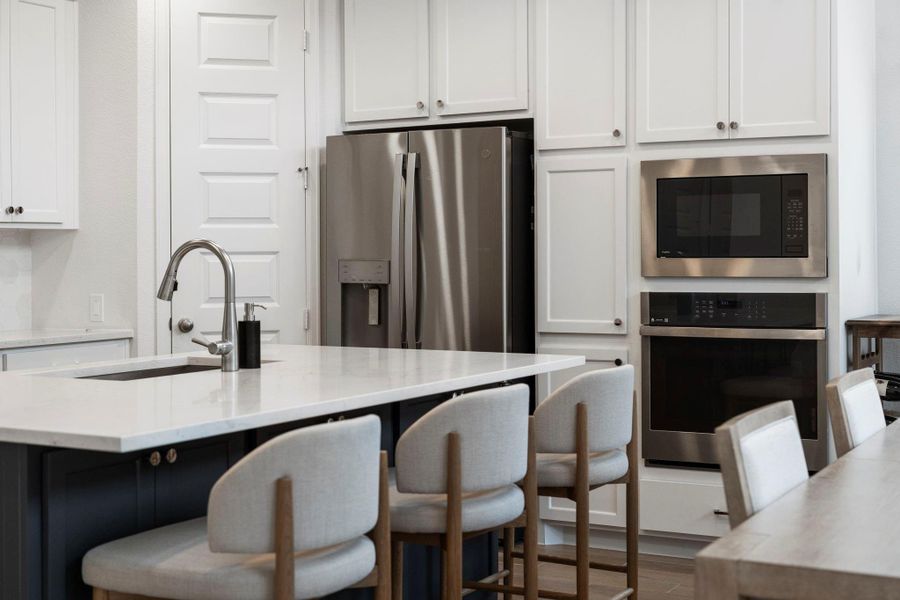 Close-up of the high-end kitchen finishes, including built-in microwave and oven, plus sleek stainless steel refrigerator. Close-up of the high-end kitchen finishes, including built-in microwave and oven, plus sleek stainless steel refrigerator.