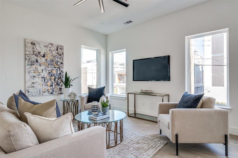 Living room featuring light hardwood / wood-style flooring, ceiling fan, and a healthy amount of sunlight