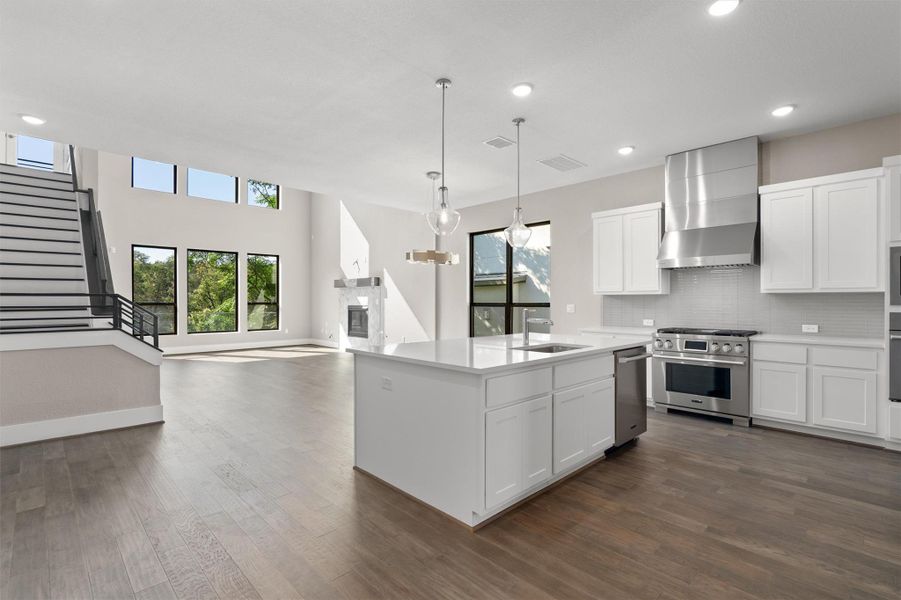 A grand, naturally illuminated interior with soaring ceilings, a modern fireplace, and a sleek kitchen island. A grand, naturally illuminated interior with soaring ceilings, a modern fireplace, and a sleek kitchen island.