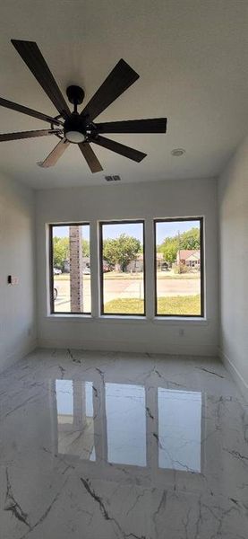 Unfurnished room featuring ceiling fan and a wealth of natural light