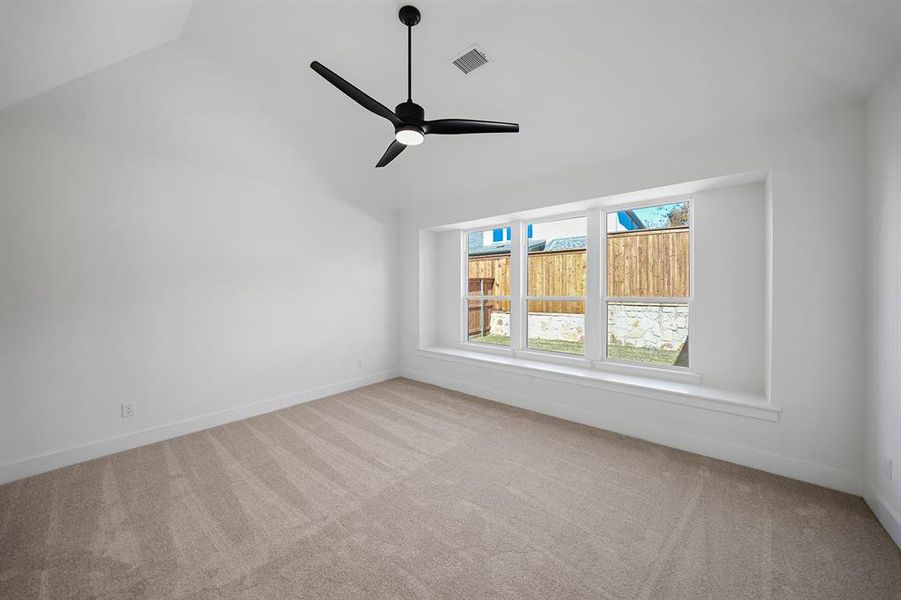 Empty room with light colored carpet, vaulted ceiling, and ceiling fan Empty room with light colored carpet, vaulted ceiling, and ceiling fan