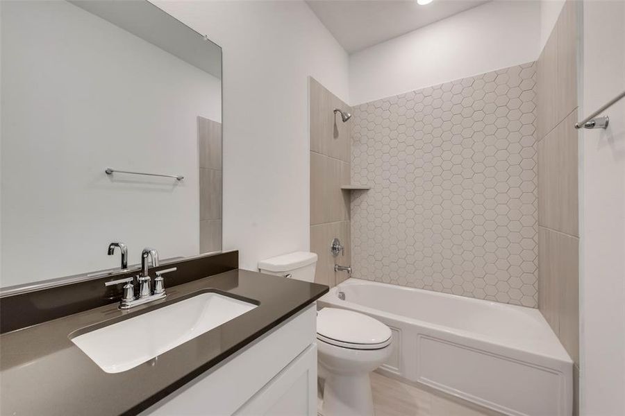 Full bathroom featuring tiled shower / bath combo, vanity, and toilet