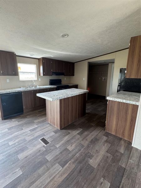 Wood-look flooring complements dark cabinetry and a central island in this functional kitchen.