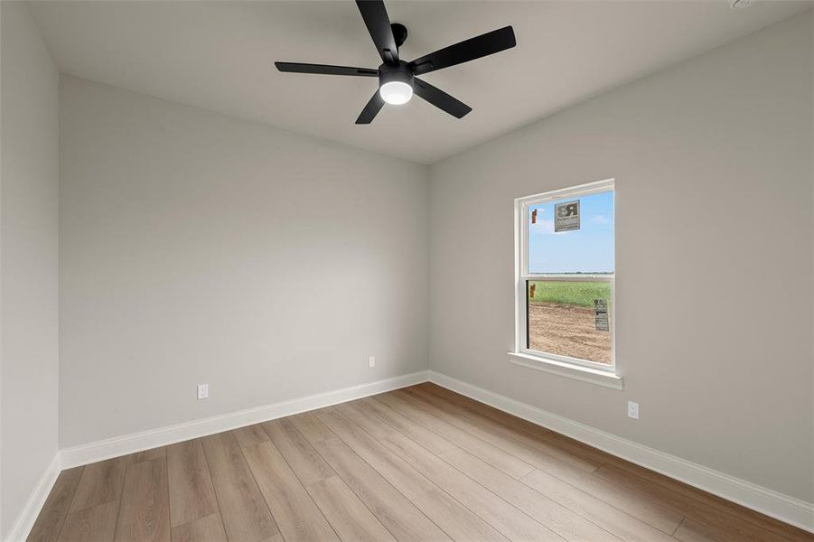 Room featuring wood-finish flooring, a ceiling fan with integrated lighting, a single window, white baseboards, and light-toned wall paint