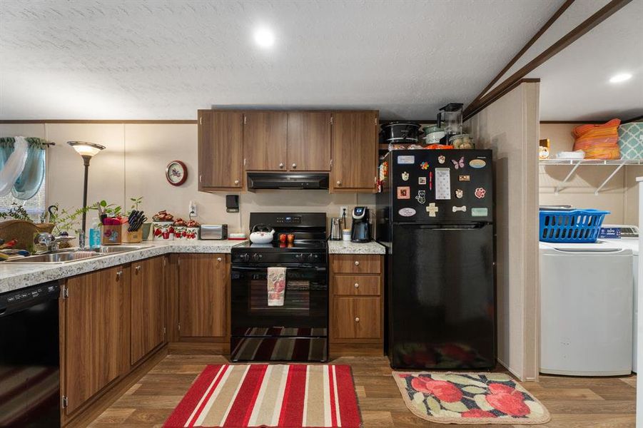 Kitchen with washer / clothes dryer, black appliances, and brown cabinets Kitchen with washer / clothes dryer, black appliances, and brown cabinets
