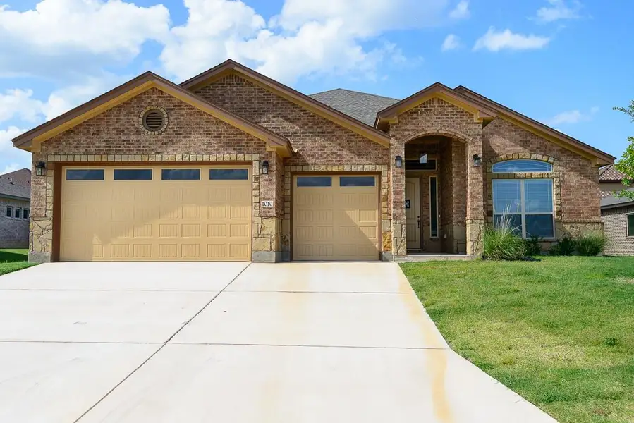 French country inspired facade featuring a garage, brick siding, concrete driveway, and a front lawn French country inspired facade featuring a garage, brick siding, concrete driveway, and a front lawn