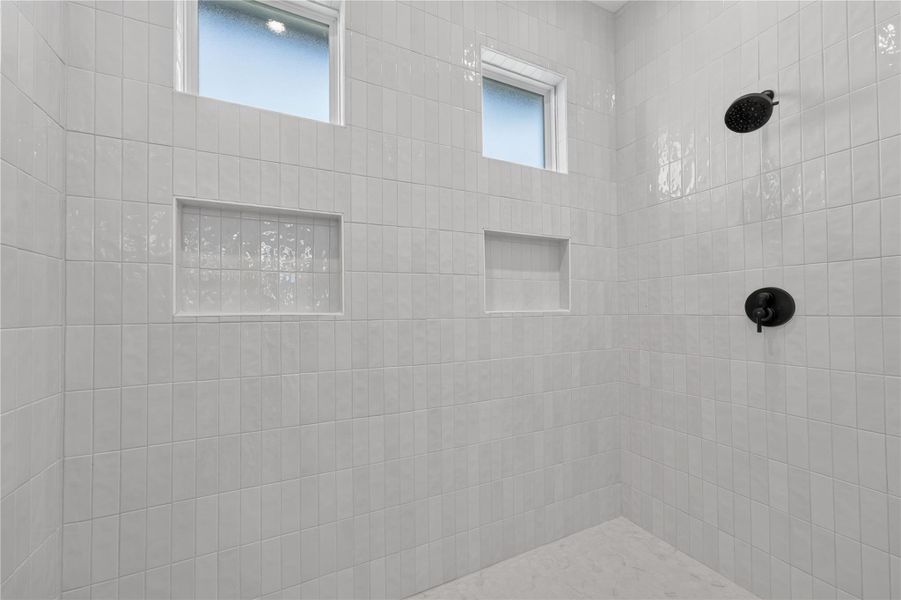 Gleaming vertical wall tiles and high windows accent this modern walk-in shower design.