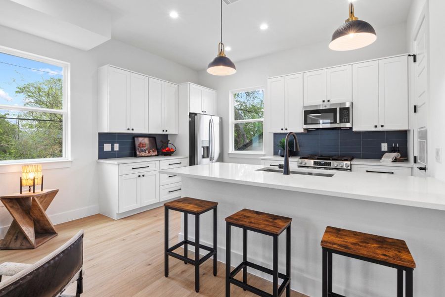 Crisp white cabinetry contrasts beautifully with a deep blue backsplash under stylish task lighting.
