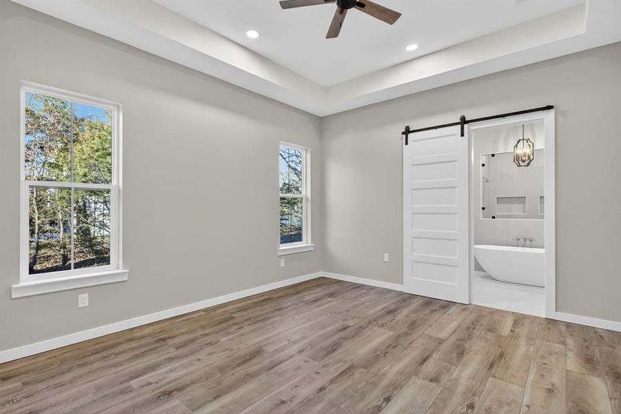 Stunning views from the master bathroom which features ceiling fan, vinyl plank flooring, and a sliding barn door leading into the master bathroom.