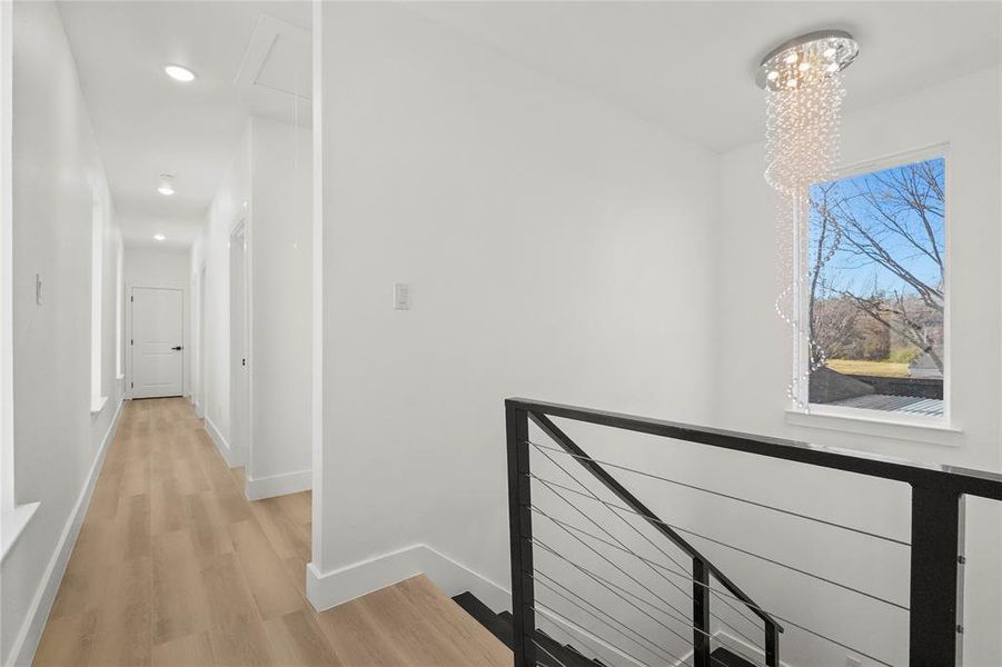 Corridor featuring an upstairs landing, light wood-style flooring, radiator heating unit, and a chandelier