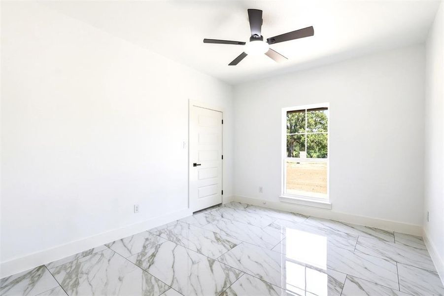 Spacious room featuring white walls, large format marble-look tile flooring, and a modern ceiling fan with integrated lighting